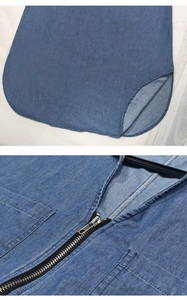 Detail view of V-neckline with silver zipper and curved hem on blue denim dress