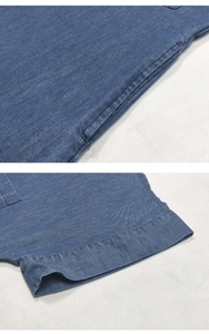 Detail of blue denim dress featuring side pocket and hem stitching on cotton fabric