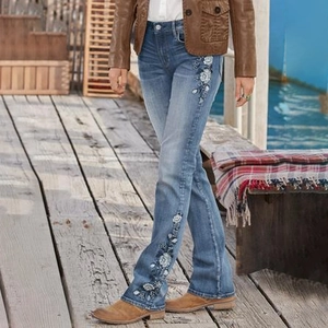 Close-up of bohemian white floral embroidery and sequins on light blue wash denim jeans