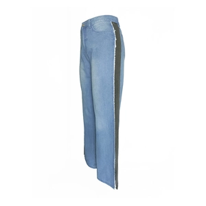 Detail of light blue wide leg jeans featuring side patchwork stripes and raw hem finish