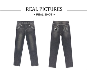 Detail view of denim jeans featuring skull and wing embroidery with rhinestone accents