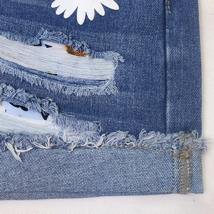 Detail of blue denim fabric with daisy print and distressed ripped floral lining