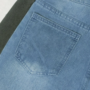 Detailed close-up showing light blue denim fabric texture and double-stitched back pocket seam
