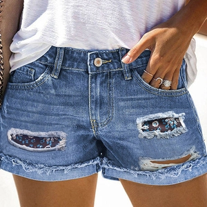 Women's light blue distressed denim shorts with floral patches and frayed hem details