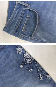 Detailed embroidery on blue denim jeans featuring dark blue floral patterns and stitching
