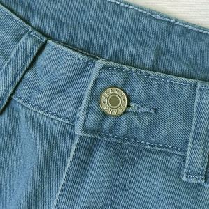 Detailed macro view of denim jeans waist with metal button and fine double-stitched seams