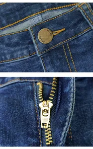 Dettaglio del bottone in ottone vintage e della cerniera dorata sui jeans blu scuro