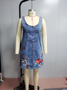 Close-up of floral embroidery on blue denim sundress with vibrant red and white details