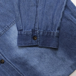 Détails de la robe chemise en jean bleu montrant le poignet avec boutons bruns et coutures