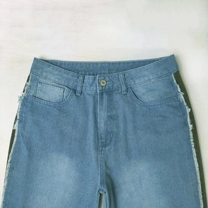 Detail of light blue wide leg jeans featuring side patchwork and frayed tassel edges