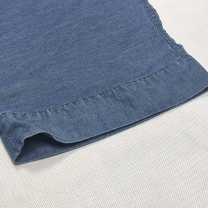 Close-up of blue denim dress hem with durable double-stitch detailing and cotton texture