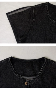 Close-up of black denim dress showing dark wash texture and amber resin button details