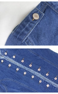 Detail view of denim jacket featuring copper star buttons and distressed fringe hem