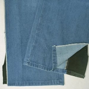 Detail of blue denim jeans leg with distressed frayed edges and contrast dark lining