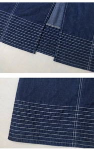 Detail eines dunkelblauen Jeansrocks mit weißen Kontrastnähten und geschlitztem Saum