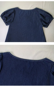 Detail der weißen Nähte an dunkelblauem Jeanskleid mit Puffärmeln und Rundhals