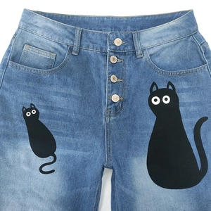 Détail du jean bleu clair à taille haute avec imprimés chats noirs et braguette boutonnée