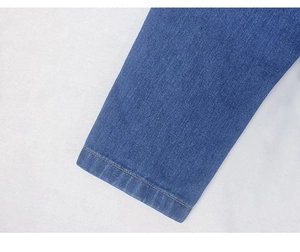 Detail of yellow contrast stitching and twill denim texture on a blue jacket sleeve