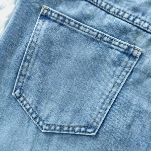 Detailed macro shot of back pocket with orange double stitching on light blue denim skirt