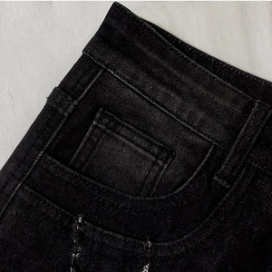 Detailed macro view of black denim jeans waistline, stitching, and retro pocket design
