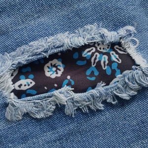 Women's light blue denim shorts featuring distressed rip design and floral pattern lining