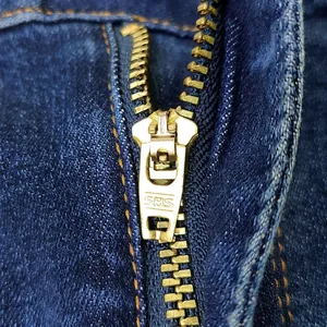 Dettaglio dei jeans a zampa elasticizzati a vita alta con cerniera in metallo dorato SBS
