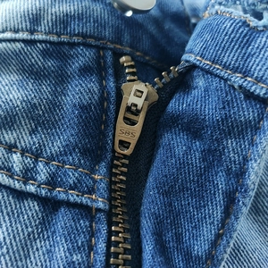 Detailed macro view of the vintage bronze SBS metal zipper on a blue denim skirt