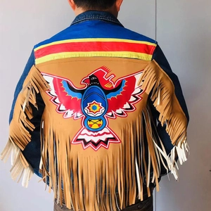 Détail d'une veste en jean bleue avec imprimé aigle graffiti et longues franges marron clair