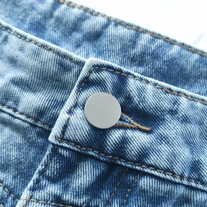 Detail of light blue denim skirt with silver metal button and premium cotton texture