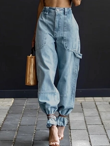 Detail view of light blue high-waisted cargo jeans with oversized pockets and ankle ties