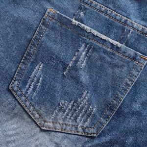 Detail of blue denim shorts showing frayed edges and stitching on the back pocket