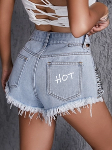 Dettaglio degli shorts in denim con borchie argentate e stampa HOT bianca sulla tasca