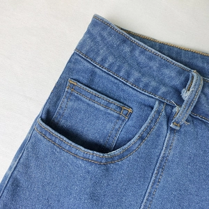 Close-up of indigo denim skirt featuring detailed gold stitching and classic watch pocket