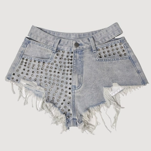 Dettaglio di pantaloncini di jeans azzurri con borchie metalliche e orli a frange lunghe