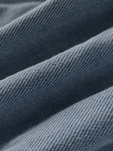Detailed macro view showing the premium light blue cotton denim fabric and twill weave texture