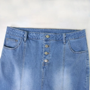 Detail of high-waisted blue denim skirt with four silver metal buttons and faded texture