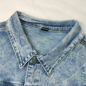 Detail of light blue snowflake wash denim jacket collar with vintage metal button