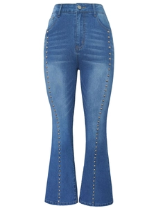 Detail of high waisted flare jeans featuring silver stud embellishments on dark denim