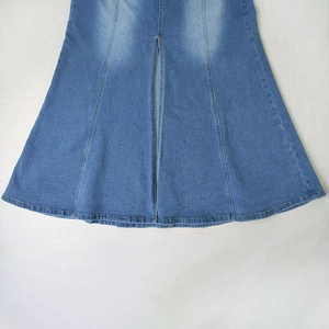 Detailed view of light wash denim skirt with front slit and multi-panel stitching