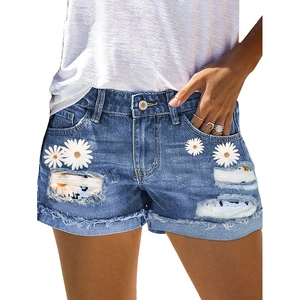 Distressed blue denim shorts featuring daisy floral prints and frayed raw hem for women