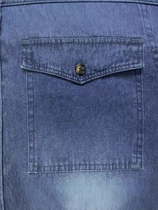 Primo piano di una camicia di jeans blu con tasca a pattina con bottone e cuciture doppie