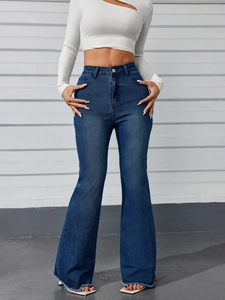 Detail view of high-waist flared jeans with distressed raw hem and vintage blue wash finish