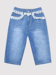 Detail of light blue denim capris featuring white floral lace embroidery on the waist