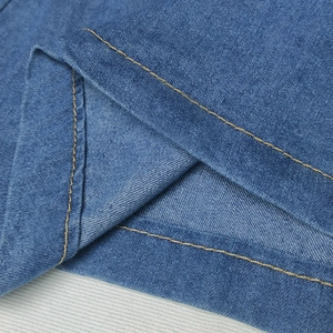 Detail view of blue denim skirt featuring golden double-stitching and fabric texture