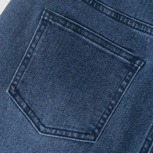 Close-up of vintage blue denim fabric showing back pocket shape and double-needle stitching