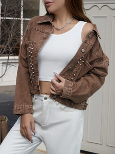 Detailaufnahme der braunen Vintage-Jeansjacke mit Nieten und gewaschener Textur