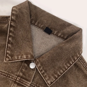 Detail eines braunen Vintage-Jeansjacken-Kragens mit silbernem Metallknopf und Naht