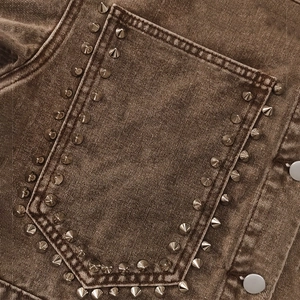 Detailaufnahme der braunen Vintage-Denimjacke mit Punk-Nieten aus Metall auf der Tasche