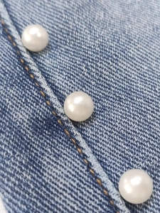 Pantaloni in denim blu con finitura tie-dye e decorazioni di perle bianche e borchie