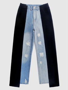 Detail of high-waist patchwork jeans with blue denim, black side panels and ripped knees